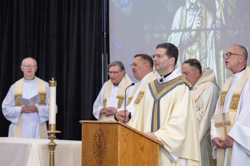 Father Maher and other priests standing at the alter singing